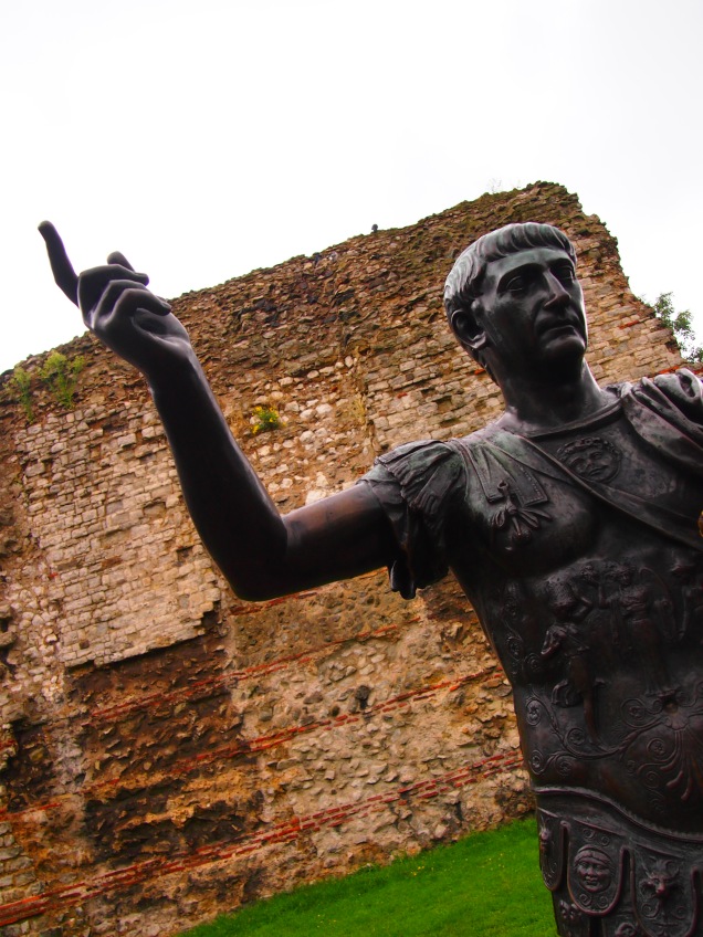 A statue of thte Emperor Trajan is located by remains of the Roman city walls near the Tower of London